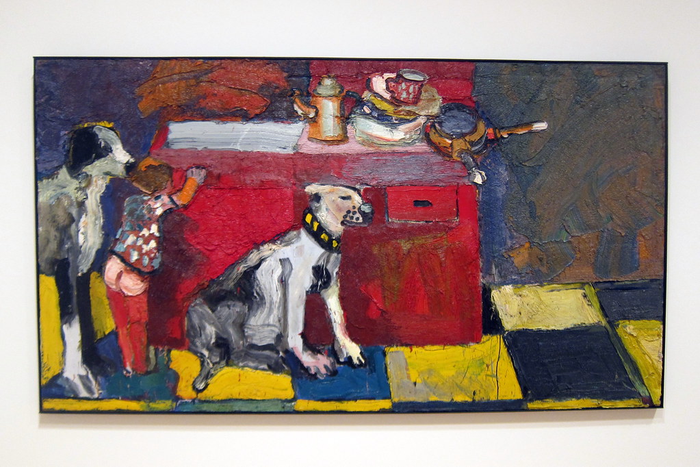 Two dogs and and young boy standing next to a counter in a kitchen