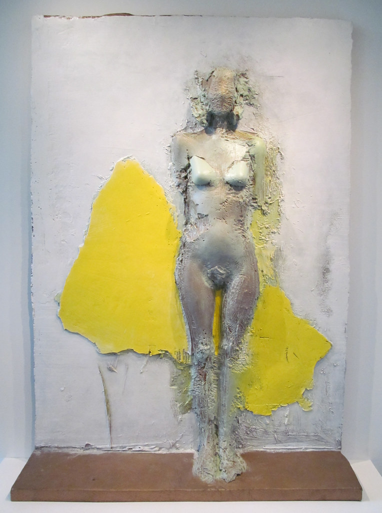 A statue of a nude woman against a yellow shape