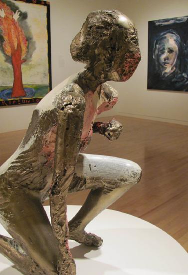 A nude woman kneeling statue with some pink paint
