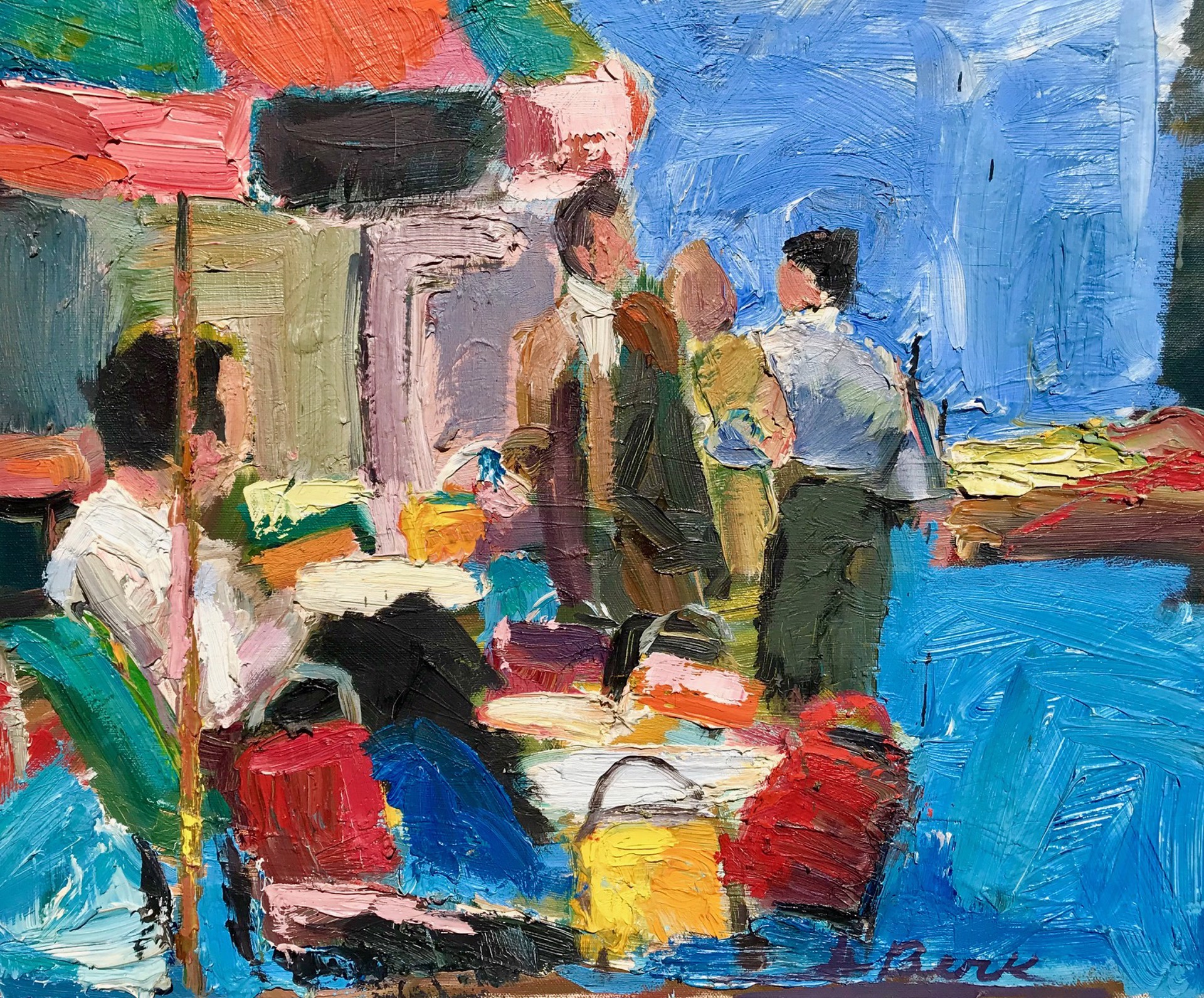 A street scene with 3 men, two standing and one sitting at a table with an orange and green umbrella