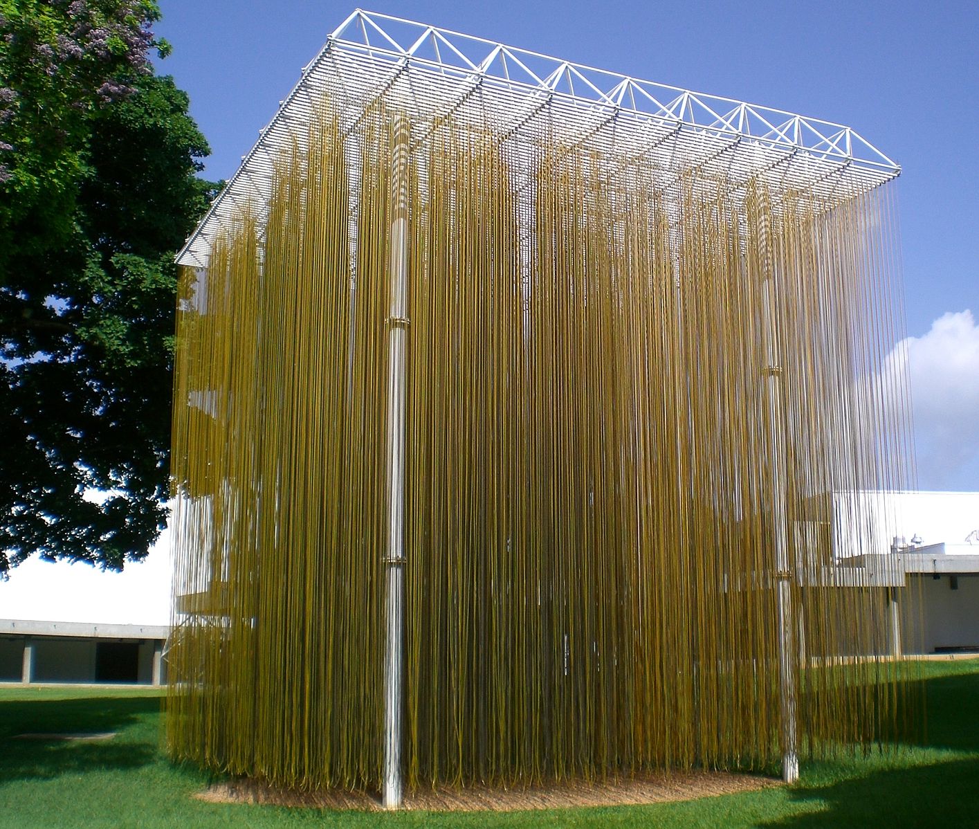 A large metal sculpture with a box frame and nylon tubes hanging down in the center