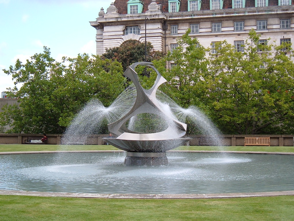 a large metal sculpture which sprays water into a pond 
