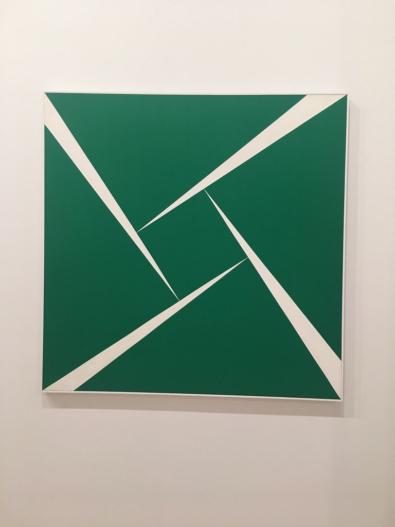 Cuatro triángulos verdes que se encuentran con un cuadrado verde sobre una pizarra blanca