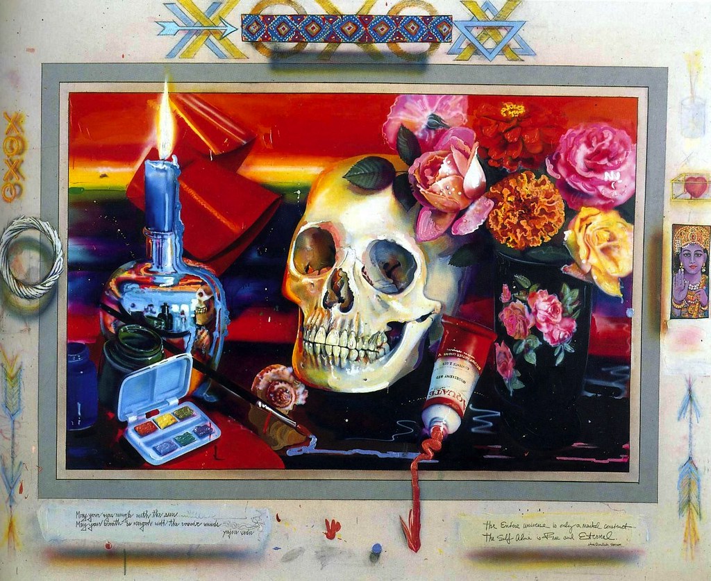A white skull on a red table cloth with a candle, flowers, and painting supplies