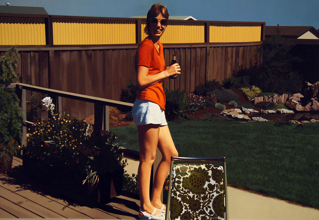 A realistic painting of a young woman wearing an orange shirt and white shorts standing in a back yard 