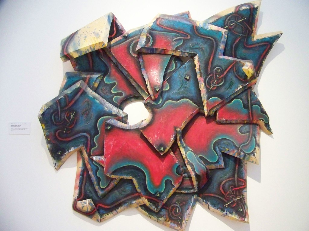 A multicolored sculpture of different shapes mounted on the wall