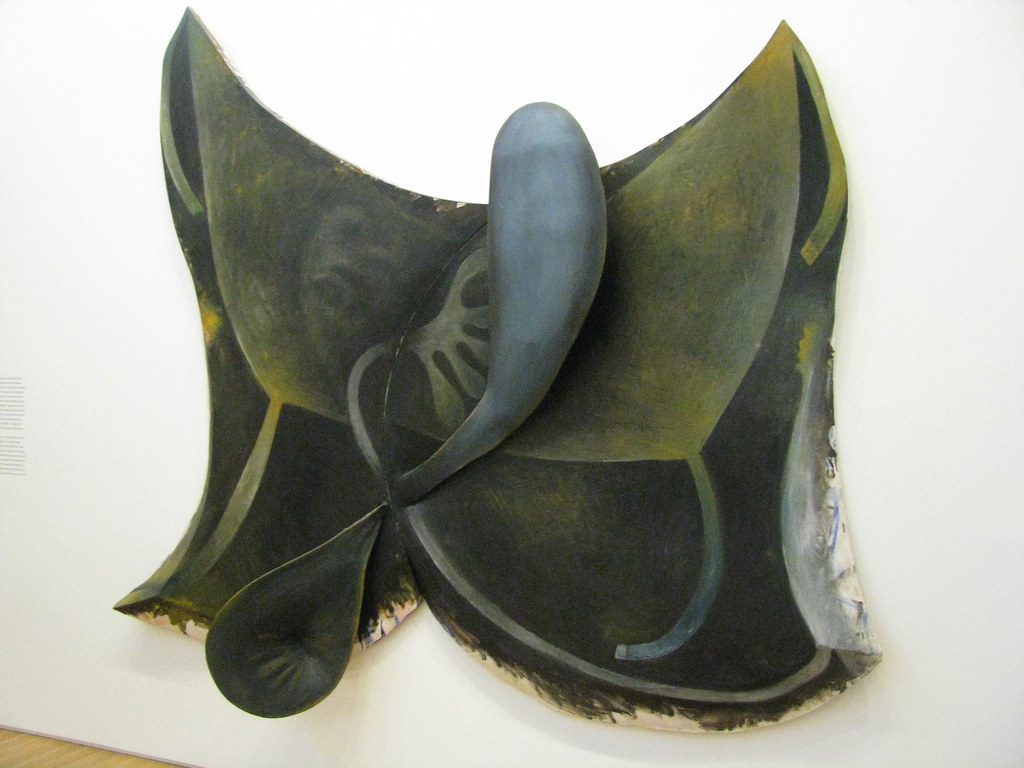 A dark colored sculpture of different shapes mounted on the wall