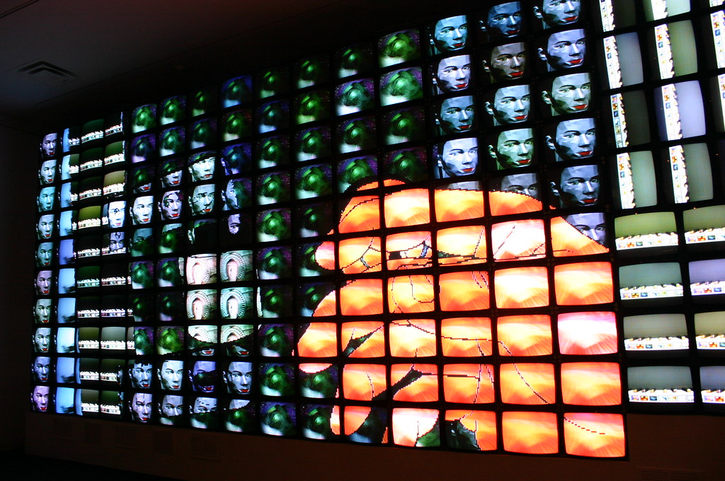 Several tv screens with a large hand reaching out