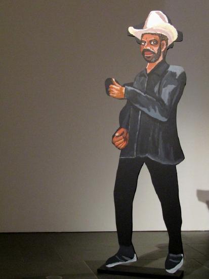 A statue of a man in black pants, black jacket and white cowboy hat