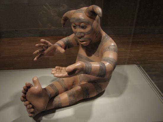 a statue from stone of a person who is sitting and looking at their hand