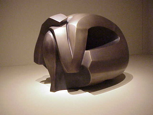 a bronze sculpture of a women squatting with her hands over her head