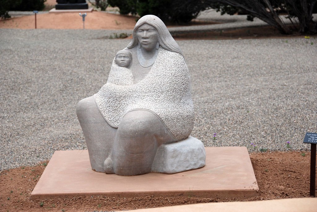 a stone woman sitting down and holding a baby