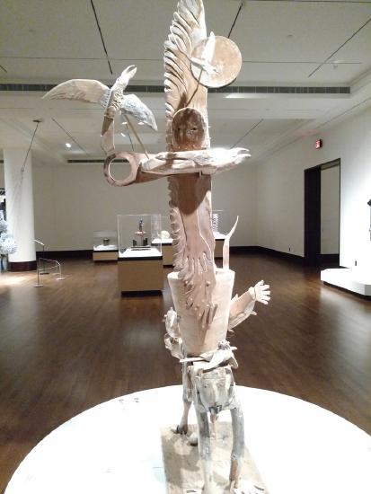 a white sculpture with a man on his hands and knees with different carvings piled on top of him