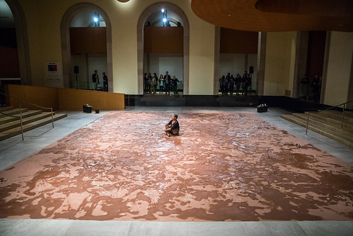 A person on a large mat in a large room sitting in the middle