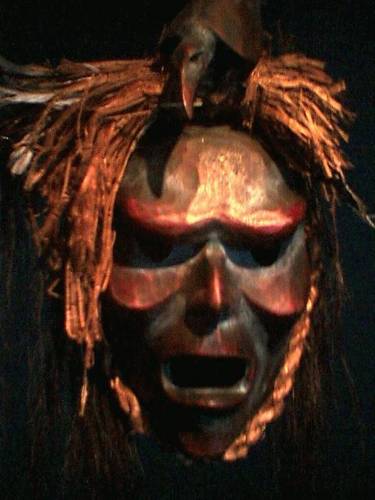 A brown mask of a man with a raven on its head