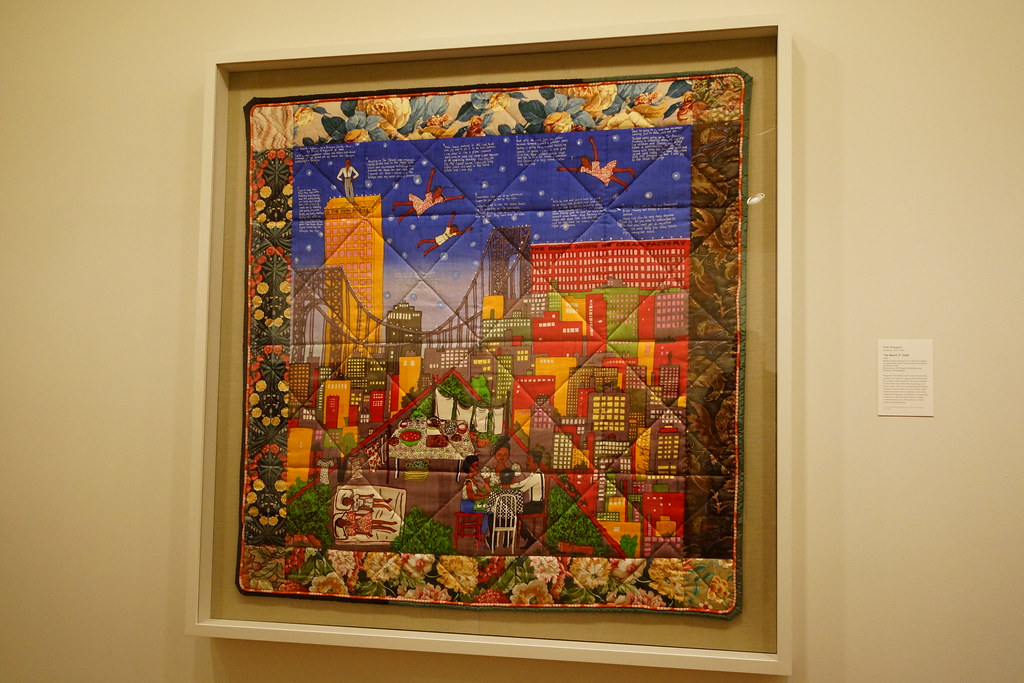 a quilt with the city scape and a family of four having dinner and laying on a blanket gazing at the stars