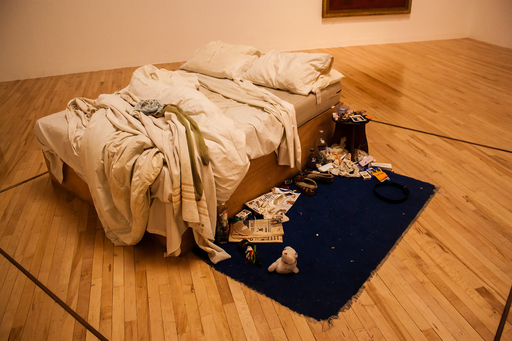 A large bed with sheets, pillows, towels with a blue carpet on the floor