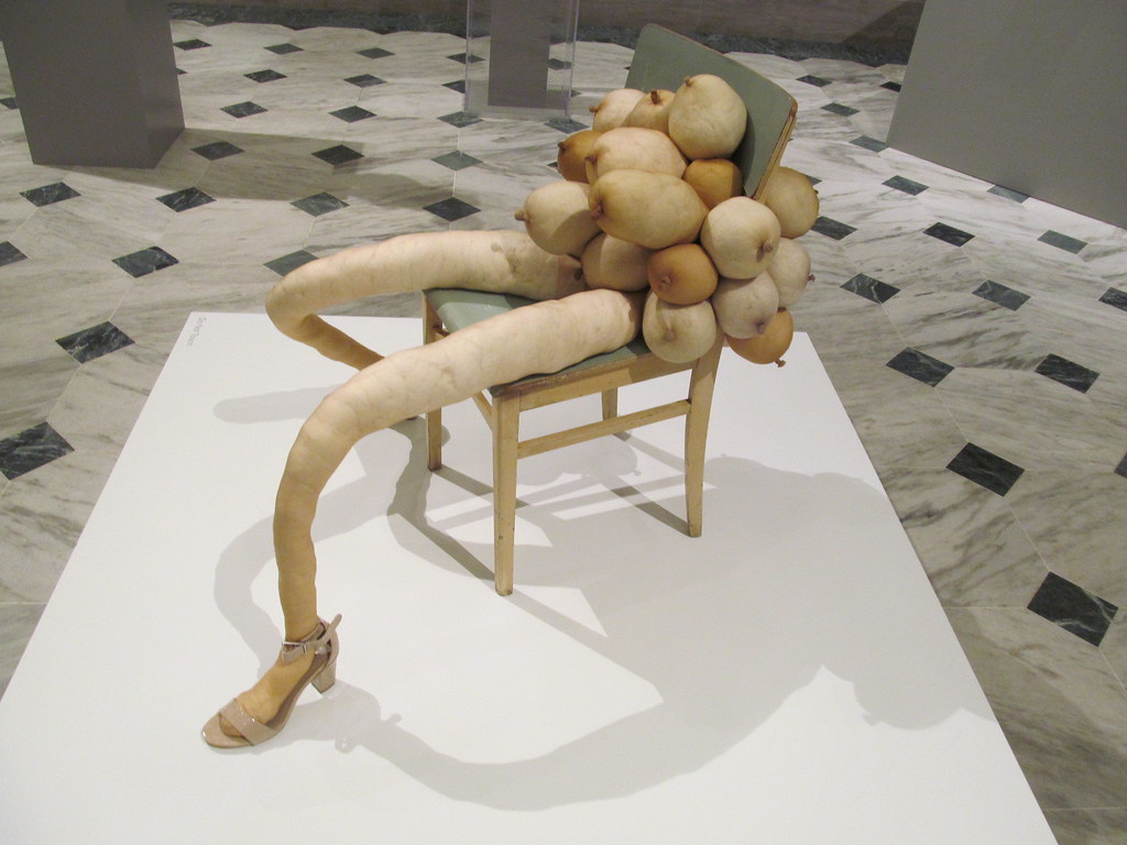 Nylons rellenos y piernas posicionadas en una silla con más nylons rellenos en forma de pechos de mujer
