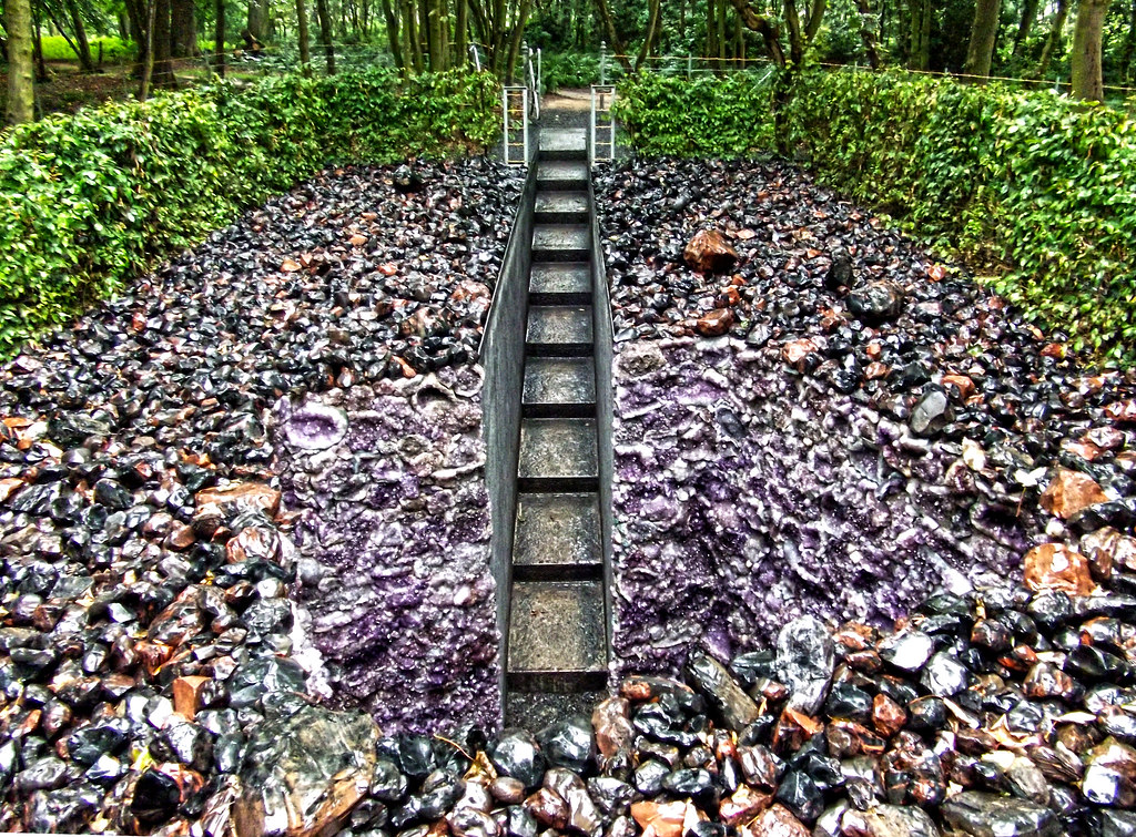 a stair way descending into a rocky pit with trees in the background