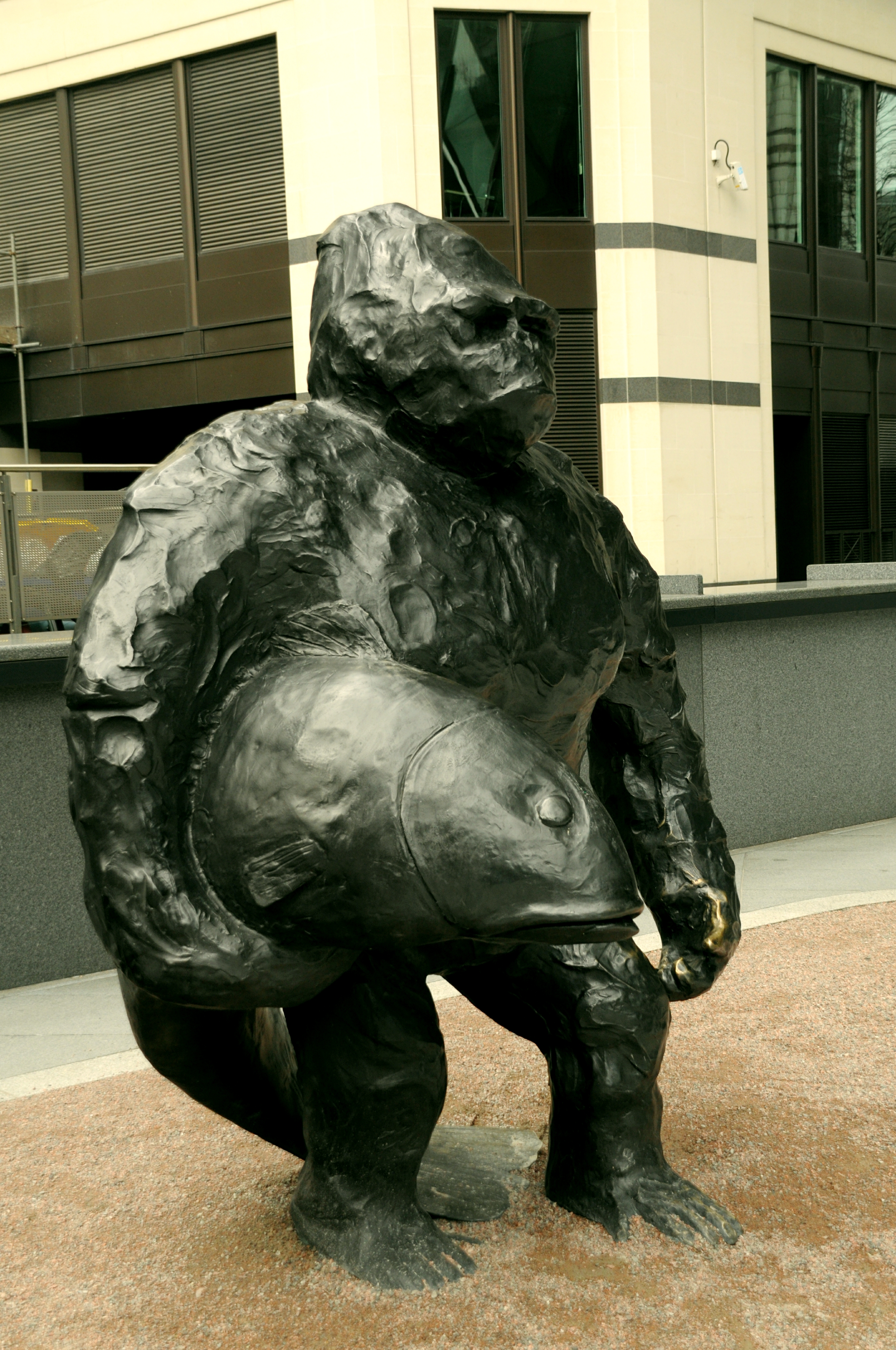 A black monkey holding a fish made out of black bronze