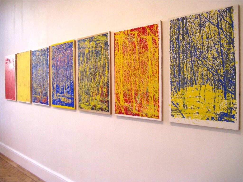 several paintings on a wall in white frames with primary colors