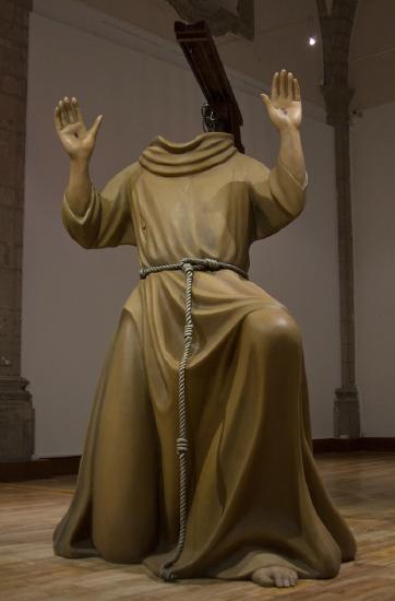 A headless man with a draped flock in tan color with hands up in the air