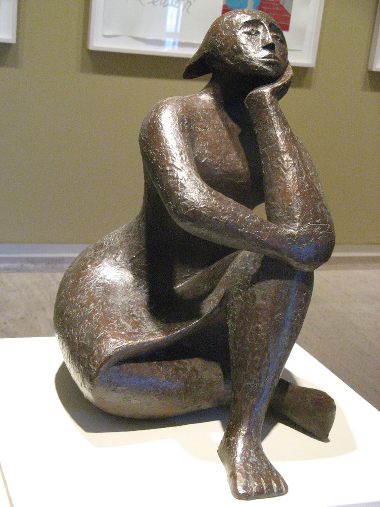 stone sculpture of a sitting woman with a knee raised and her arm on her chin