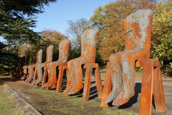 painted concrete sculpture of saw horses and headless bodies sitting on them