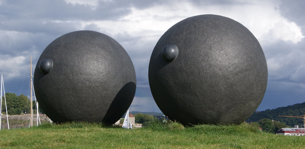 Two large granite balls on grass with two small balls on the side