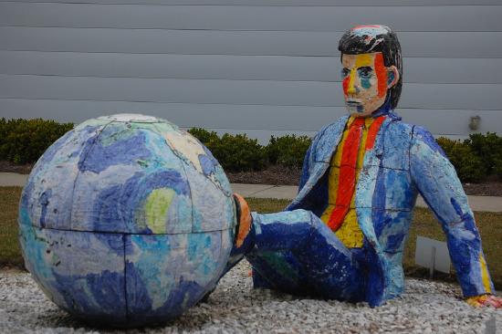 a statue of a man sitting on the ground with his feet on the world