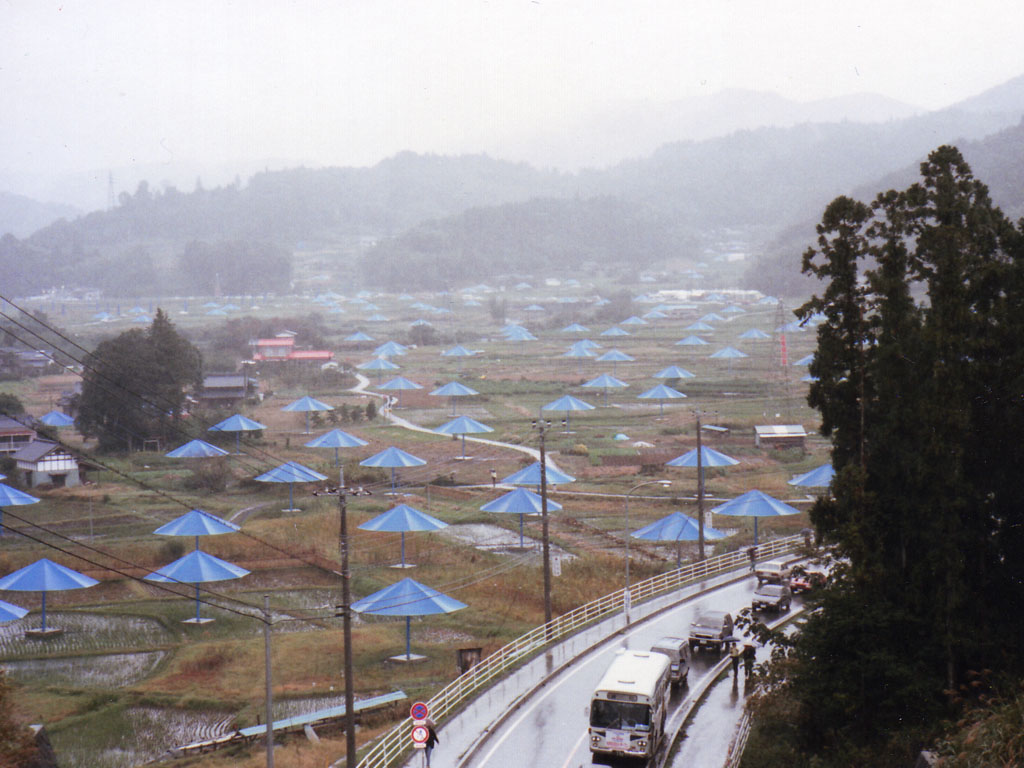 blue umbrellas scattered in a landscape of green grass