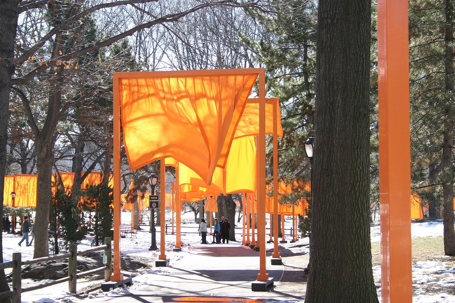 Large orange poles drapped with orange fabric in a tree lined park