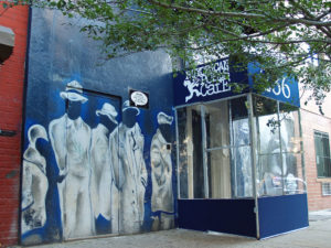 la entrada del Nuyorican Poets Cafe tiene un mural pintado dramático con personas vestidos en blanco contra un trasfondo azul