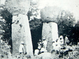 foto de dos piedras latte con hombres al lado: los pilares son al menos once o doce pies de altura, con las piedras redondas encima que añaden otros cuatro pies más