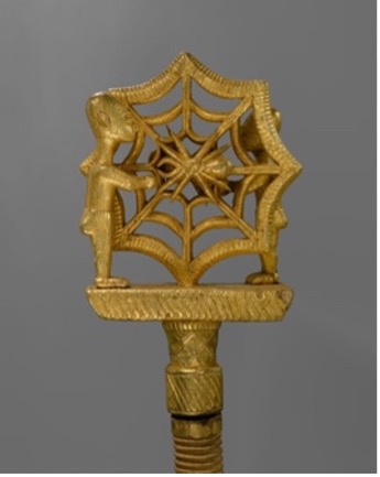 a gold staff in the shape of a spider web with a spider in the middle