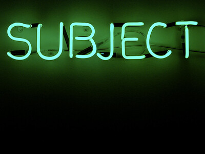 The word "subject" lit up in neon against a black background.