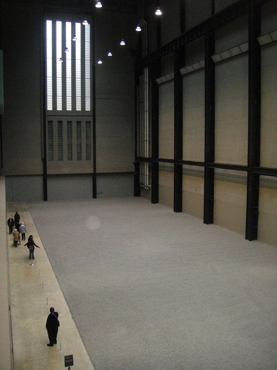 Un gran edificio hecho de concreto y acero con semillas de girasol repartidas por todo el piso