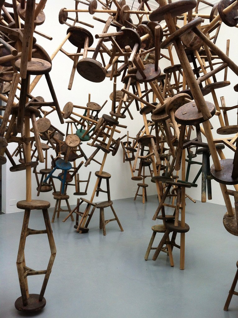varios taburetes de madera pegados entre sí en una escultura muy grande