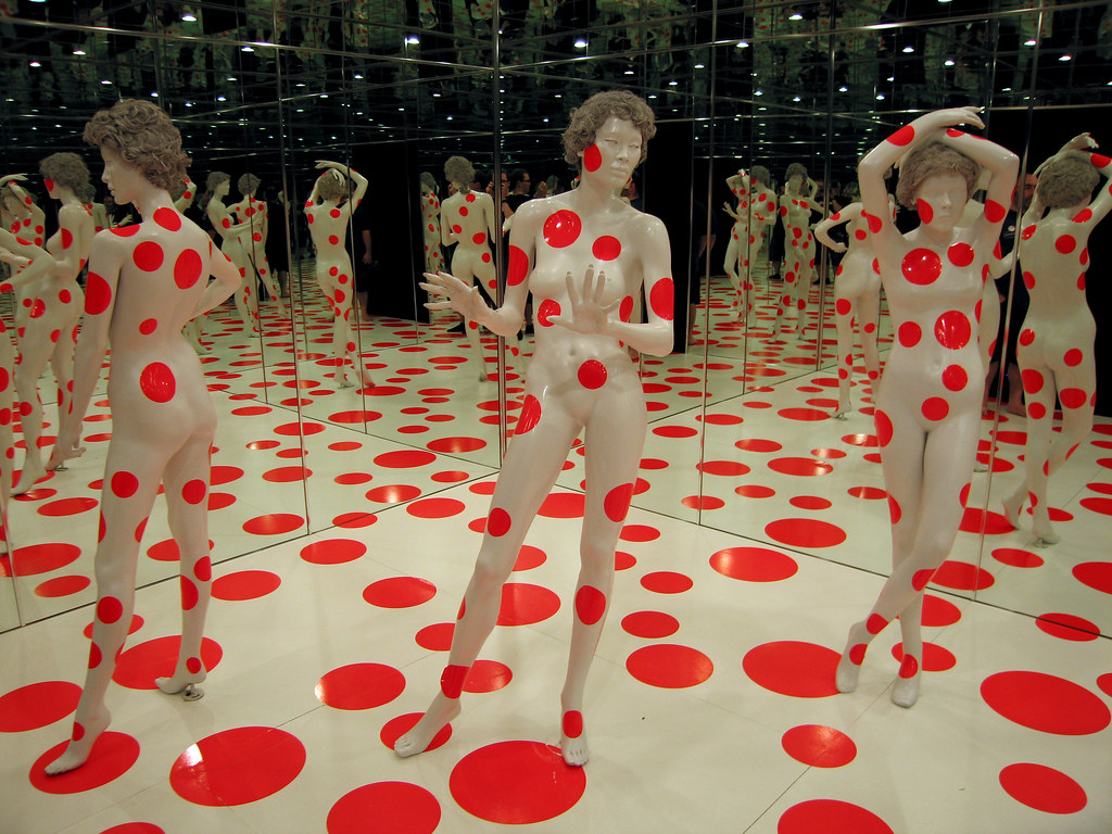 una habitación llena de espejos y maniquíes pintados de blanco con lunares rojos