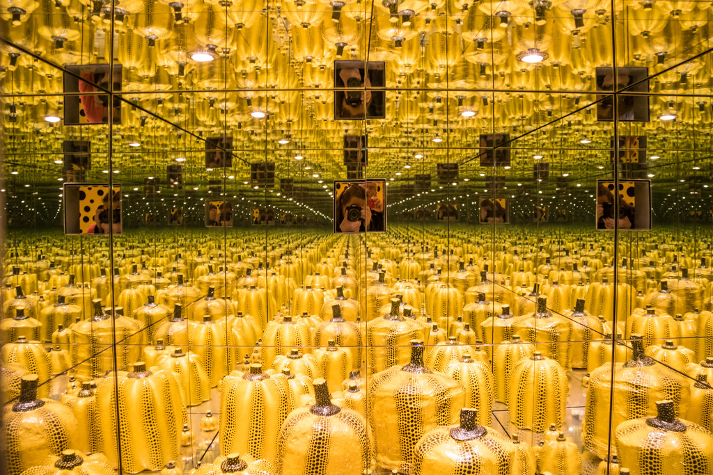 a mirrored room with hundreds of painted pumpkins in yellow with black polka dots