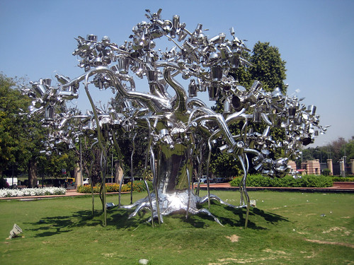 un árbol afuera en un césped hecho de objetos metálicos