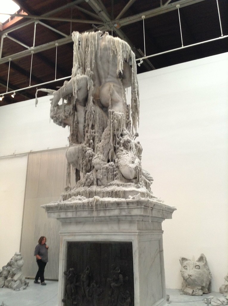 una estatua de gentes3 con cintas de barro en un pedestal