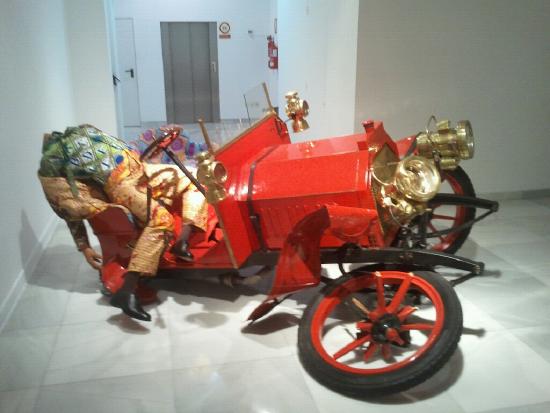 an old red car that is partially wrecked with a headless body in bloody clothes