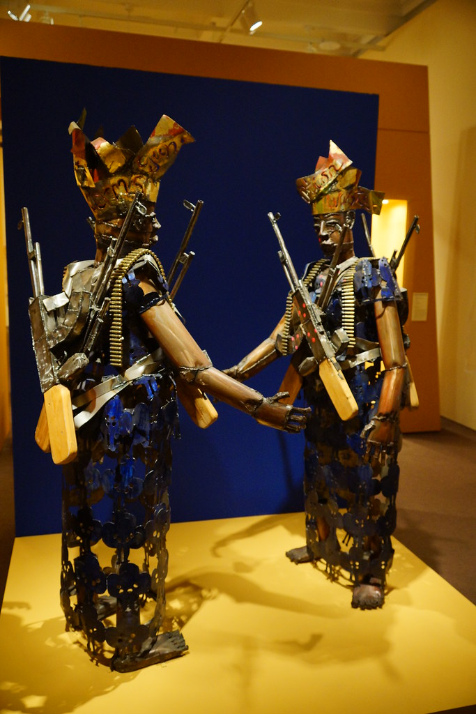 two metal sculptures with headdresses and guns