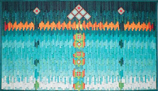 a sewn pieced fabric in teals, oranges and blacks stacked on top of each other