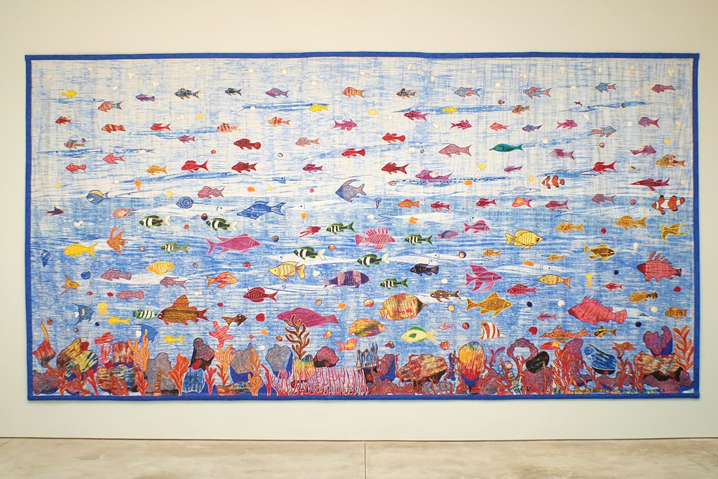 an underwater scene with coral and hundreds of fish on a blue background