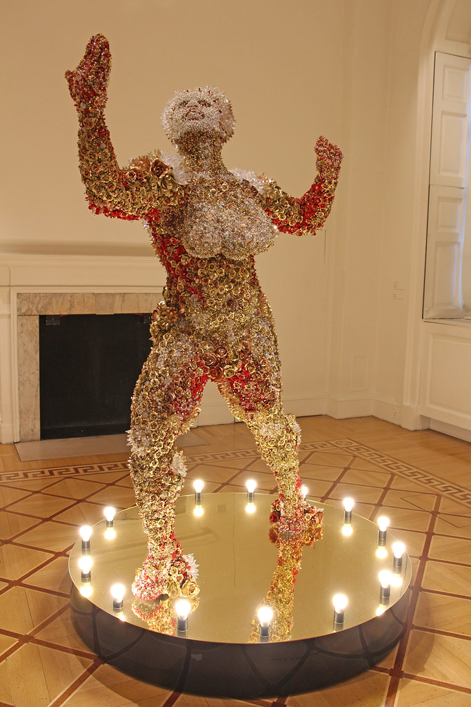 metal sculpture of a nude woman in colors of gold and some red