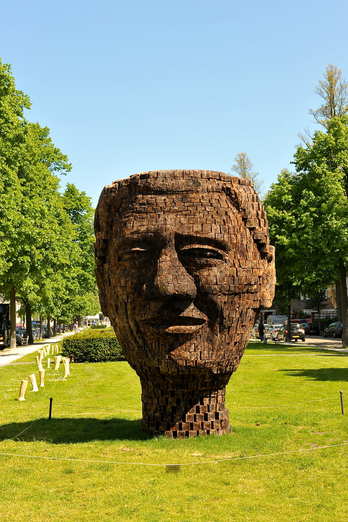 a wooden sculpture of a mans face on grass