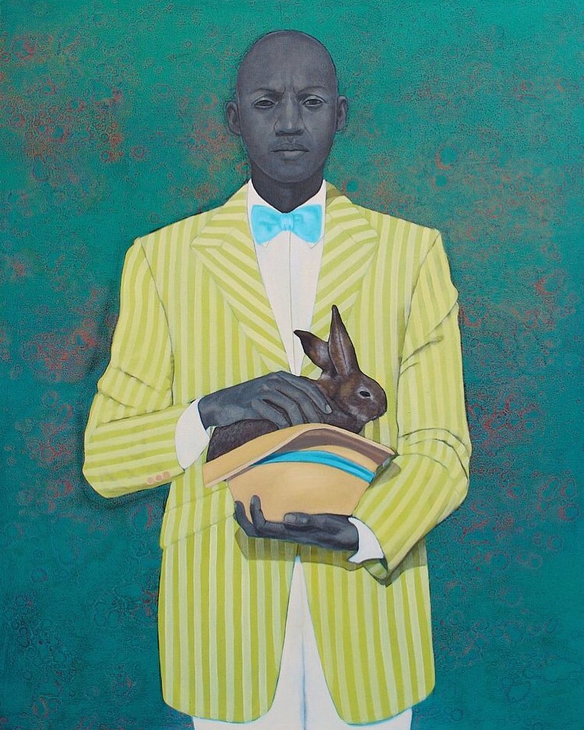 A man in a white and green striped suit holding a bunny in a hat