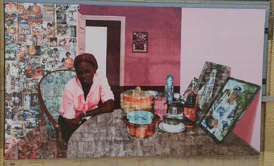 a woman sitting at a dining room table with pink walls and pictures on the walls